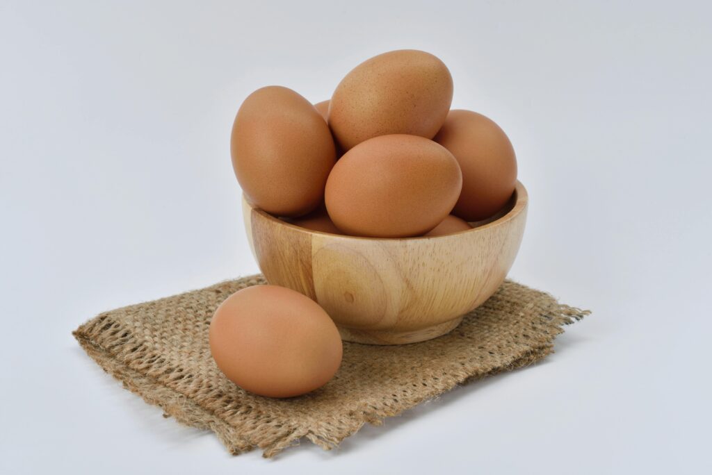 High resolution image of brown eggs in a wooden bowl placed on burlap fabric, ideal for food-themed content.