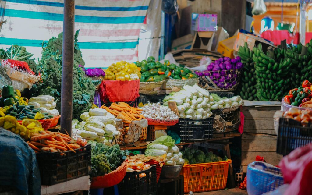 Vibrant array of fresh fruits and vegetables displayed at a bustling market stall.