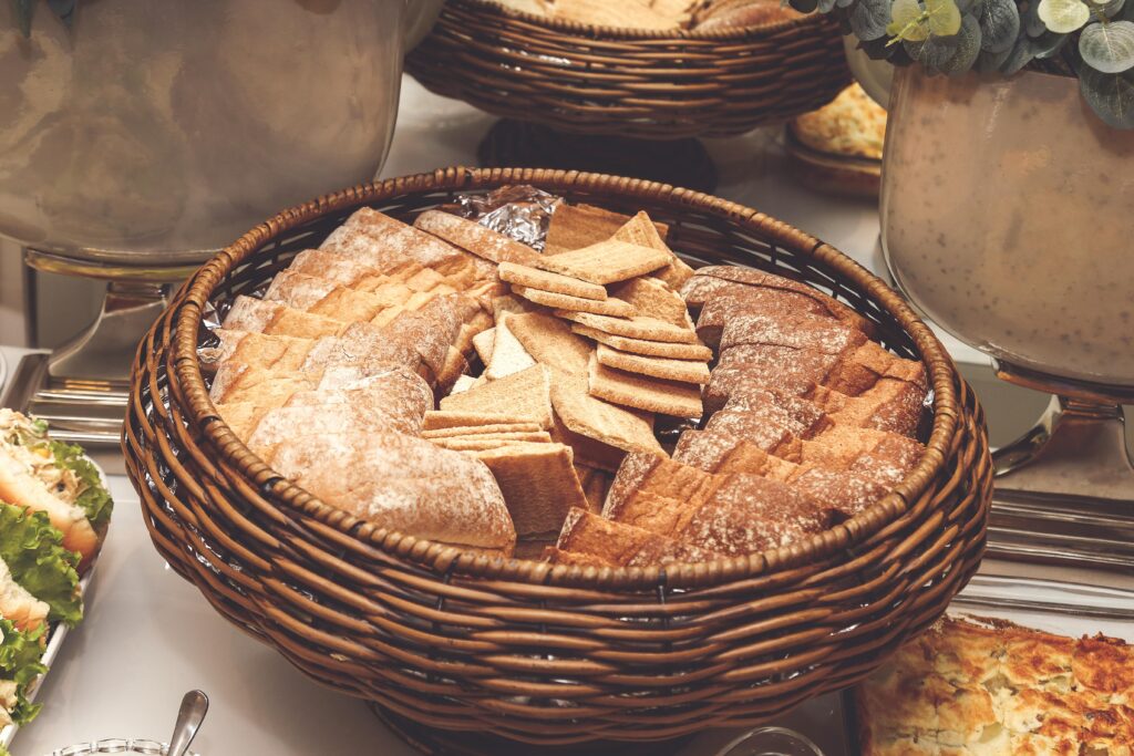 A wicker basket filled with assorted breads and crackers, perfect for a buffet setting.