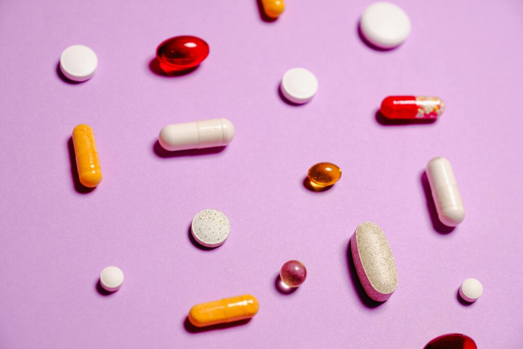 Various colorful pills and capsules scattered on a purple surface, representing healthcare and medication.