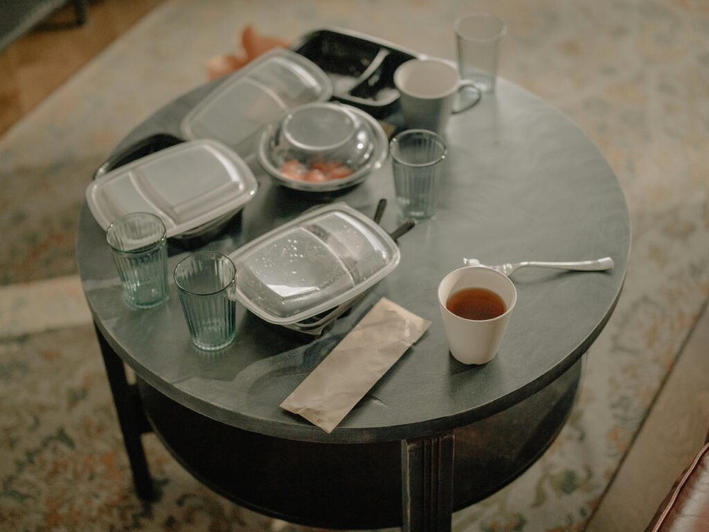 A cozy home setting with a table covered in takeaway food containers and used dishes.