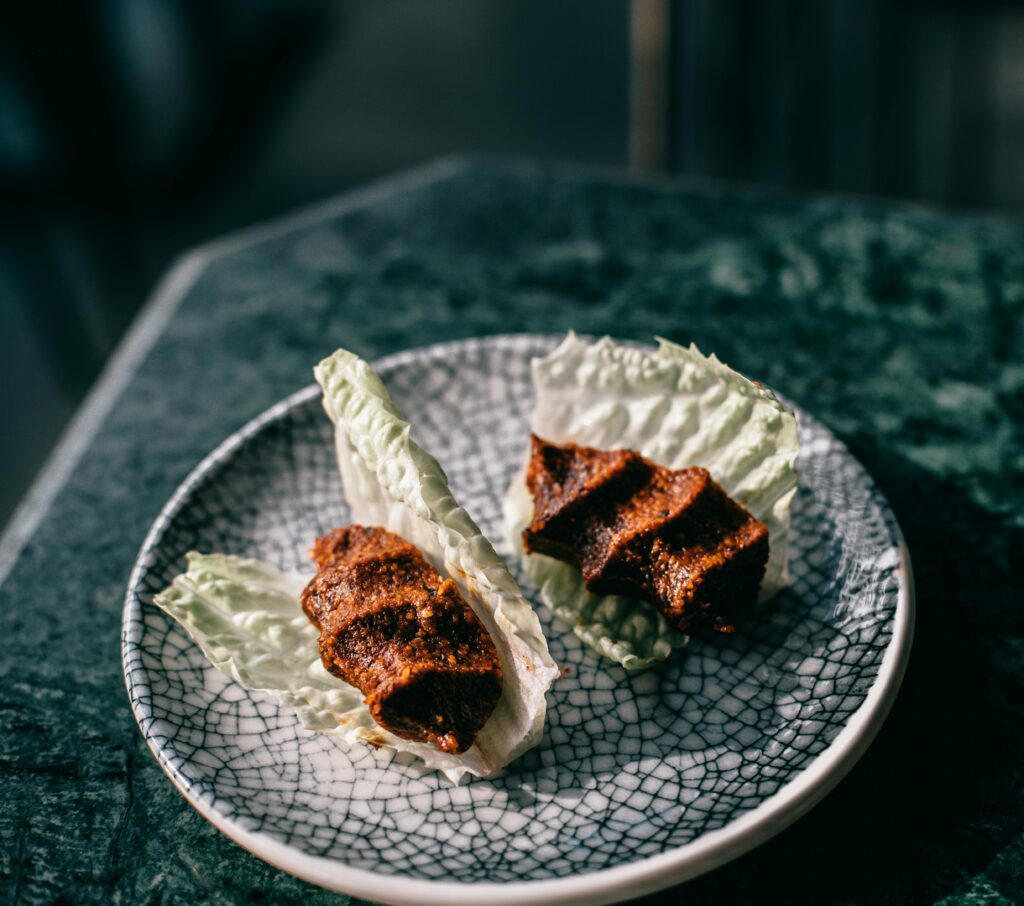 Close-up of Turkish Cig Kofte on lettuce leaves, beautifully presented on a decorative plate.