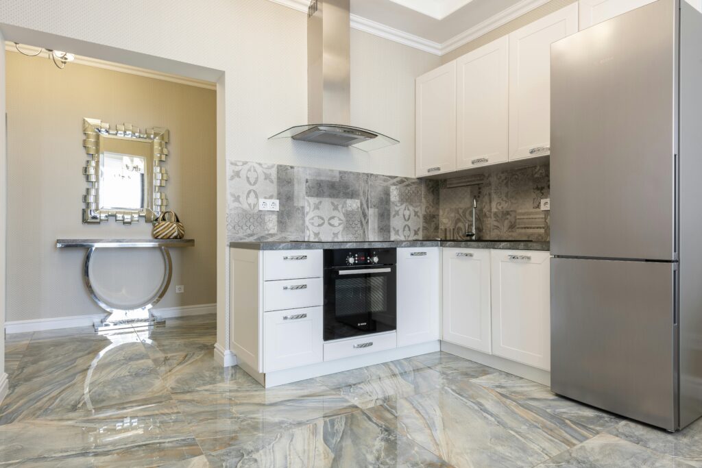 Stylish contemporary kitchen featuring stainless steel appliances, marble floors, and geometric design.