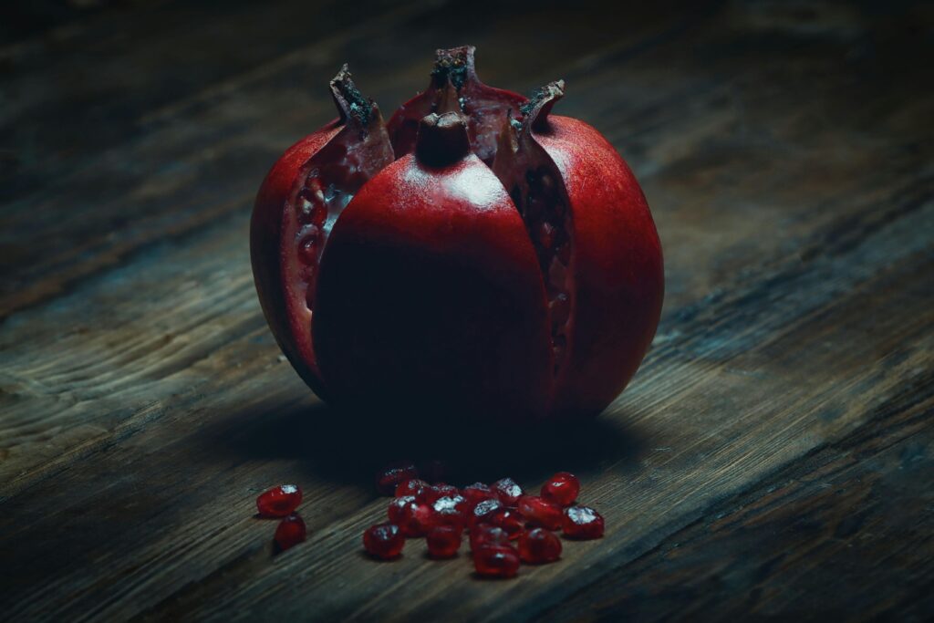 Fresh pomegranate on a rustic wooden table showcasing vibrant seeds.